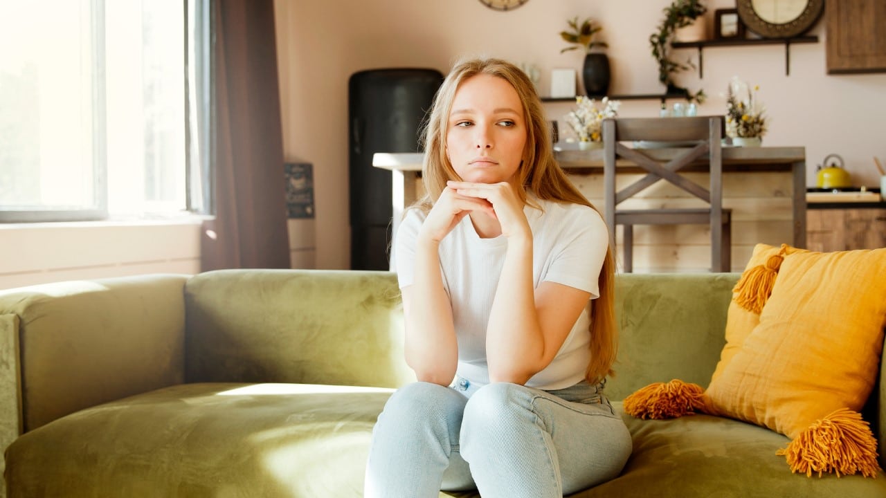 Woman sitting on a couch looking sad.