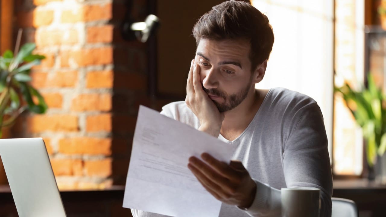 Man looking at documents and budget. Worried about taking on more debt.