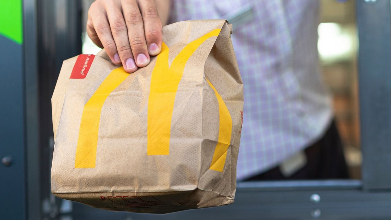 Sankt-Petersburg/Russia - July 21 2019: McDonalds worker holding bag of fast food. Hand with a paper bag through the window of mcdonalds car drive thru service.