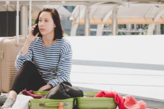 Woman on her phone by luggage.