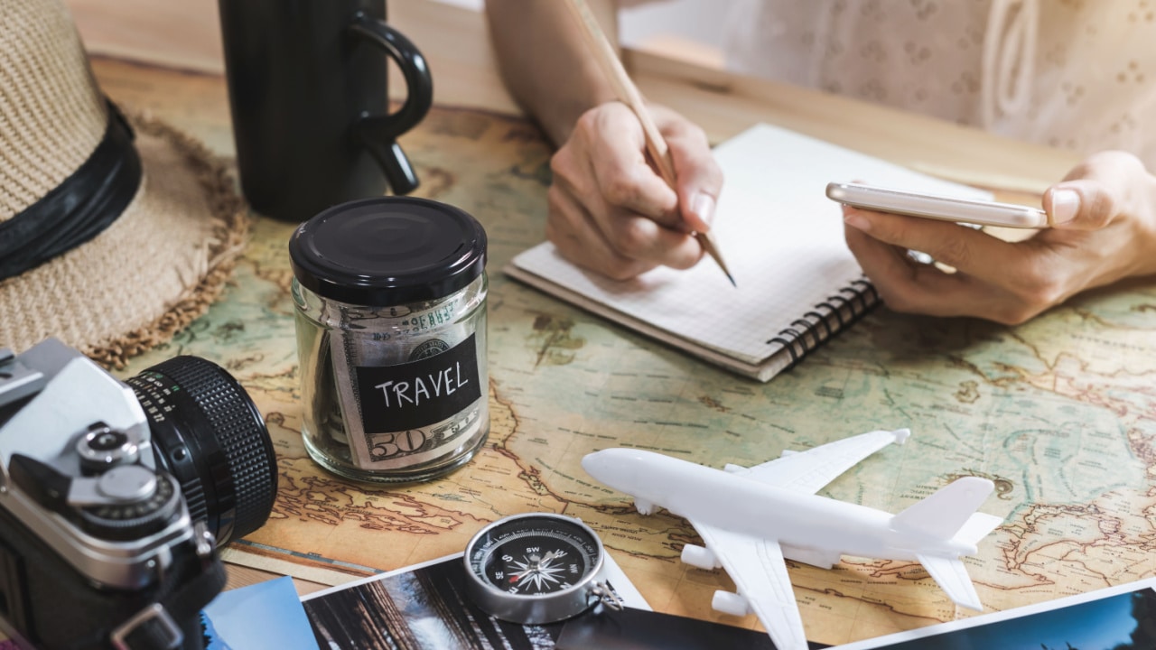 Planning travel on a budget, map, notebook, money jar