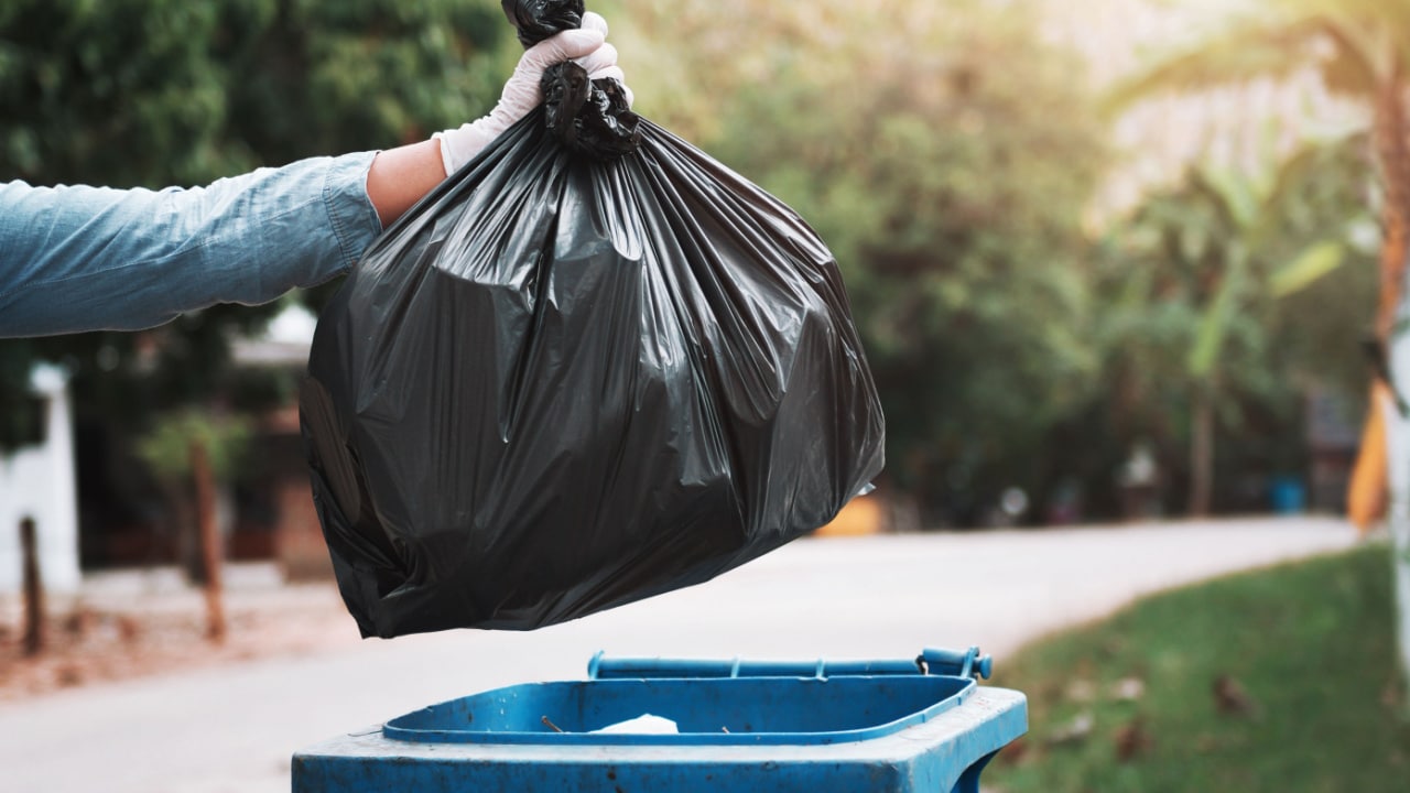 Person throwing food away in garbage can