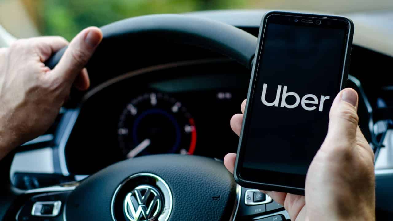 Uber driver holding smartphone in Volkswagen car.