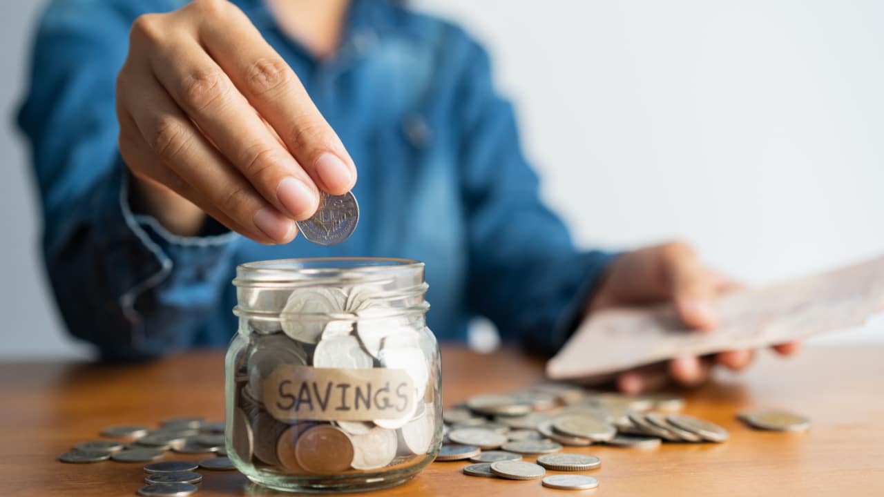 Woman putting money into a jar.