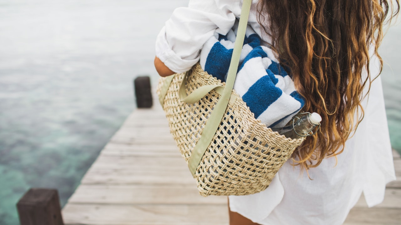 Girl carrying bag containing beach towel