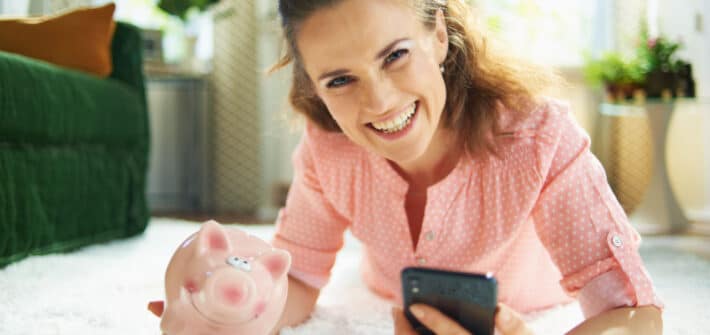 Happy woman holding a piggy bank.