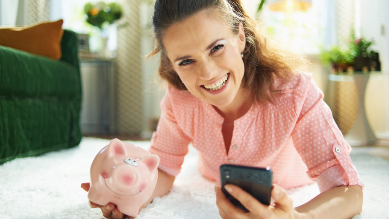 Happy woman holding a piggy bank.