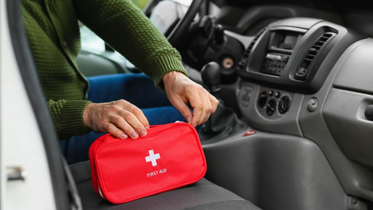 Man opening first aid kit in a car.