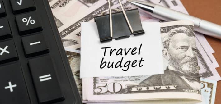 Calculator and money in a clip with note saying 'travel budget'