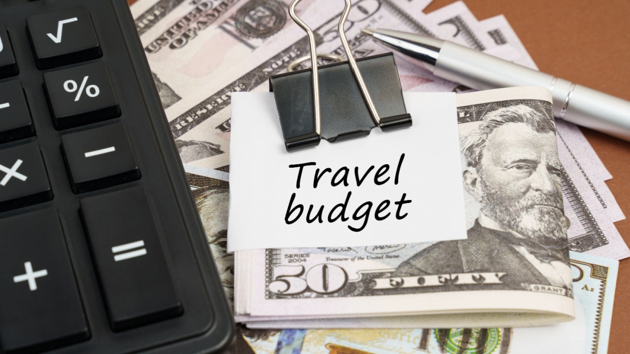 Calculator and money in a clip with note saying 'travel budget'
