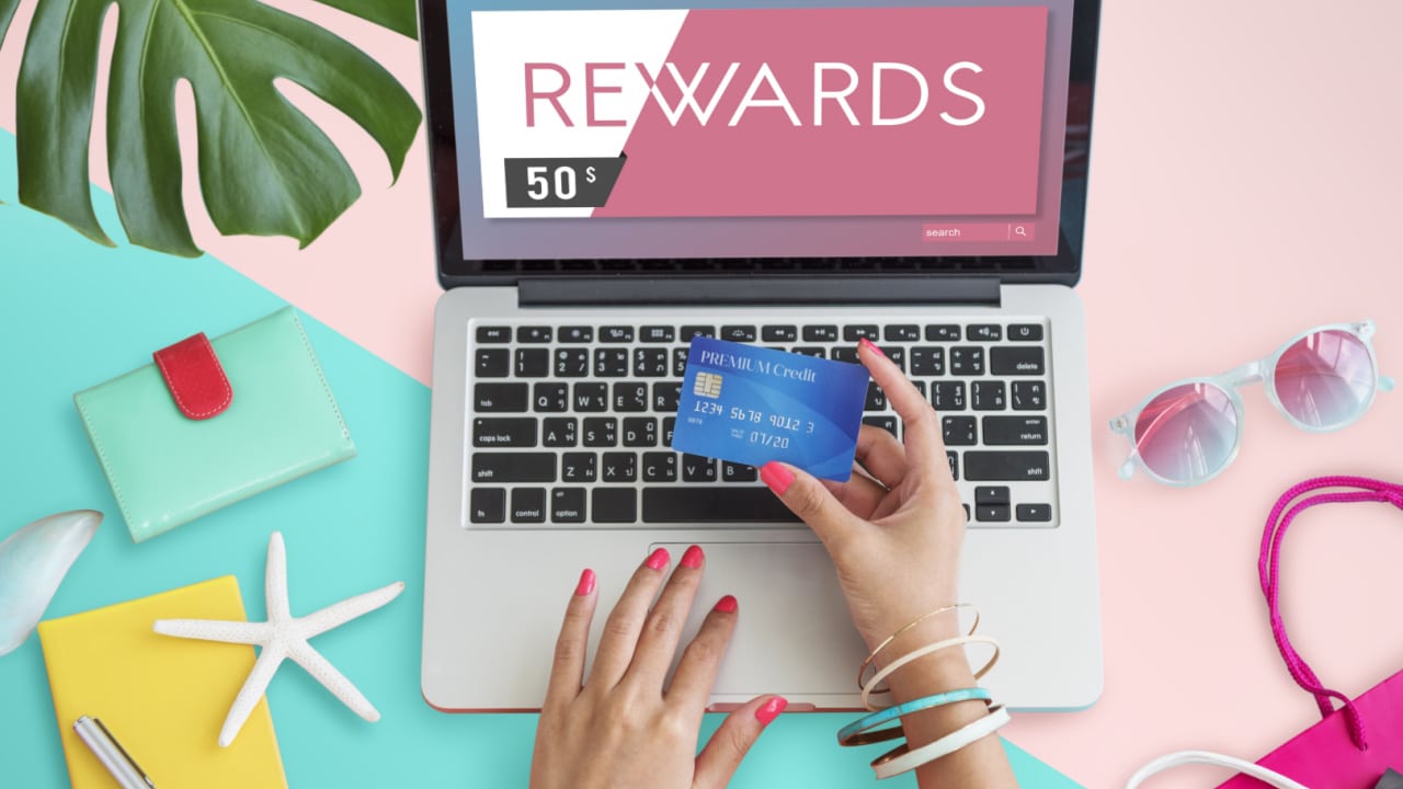 Woman with credit card out looking at rewards on laptop