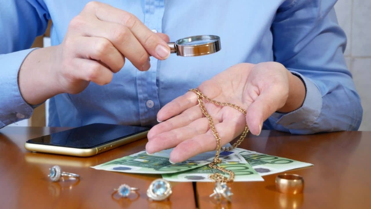Pawnshop worker verifying jewellery and photo or video camera and give money.