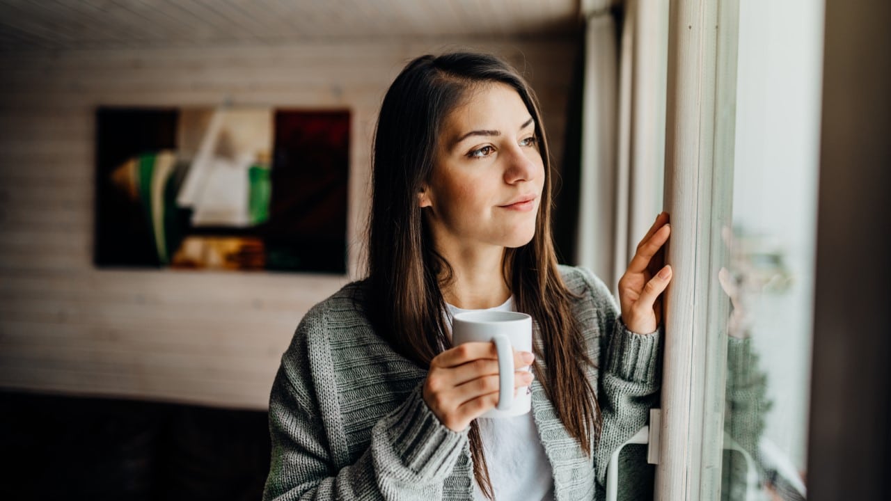 young woman enjoying cup of tea looking out the window