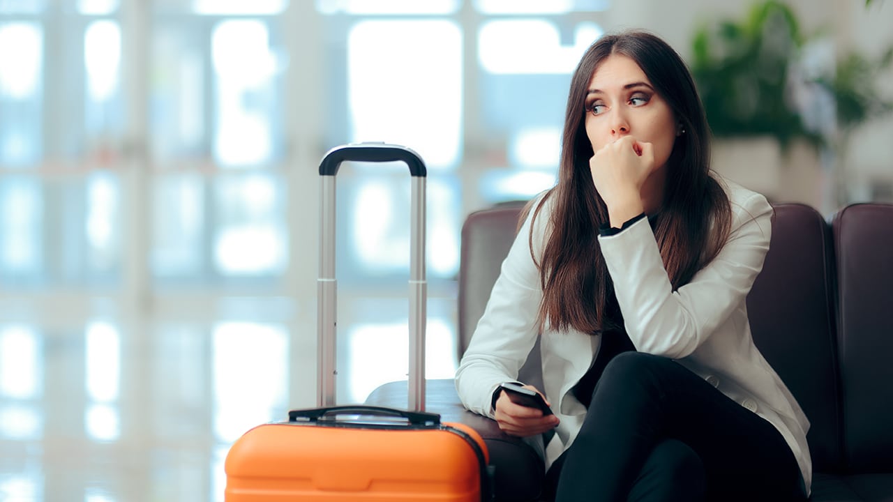 Sad Melancholic Woman with Suitcase in Airport Waiting Room. Upset girl traveling along waiting for the next flight