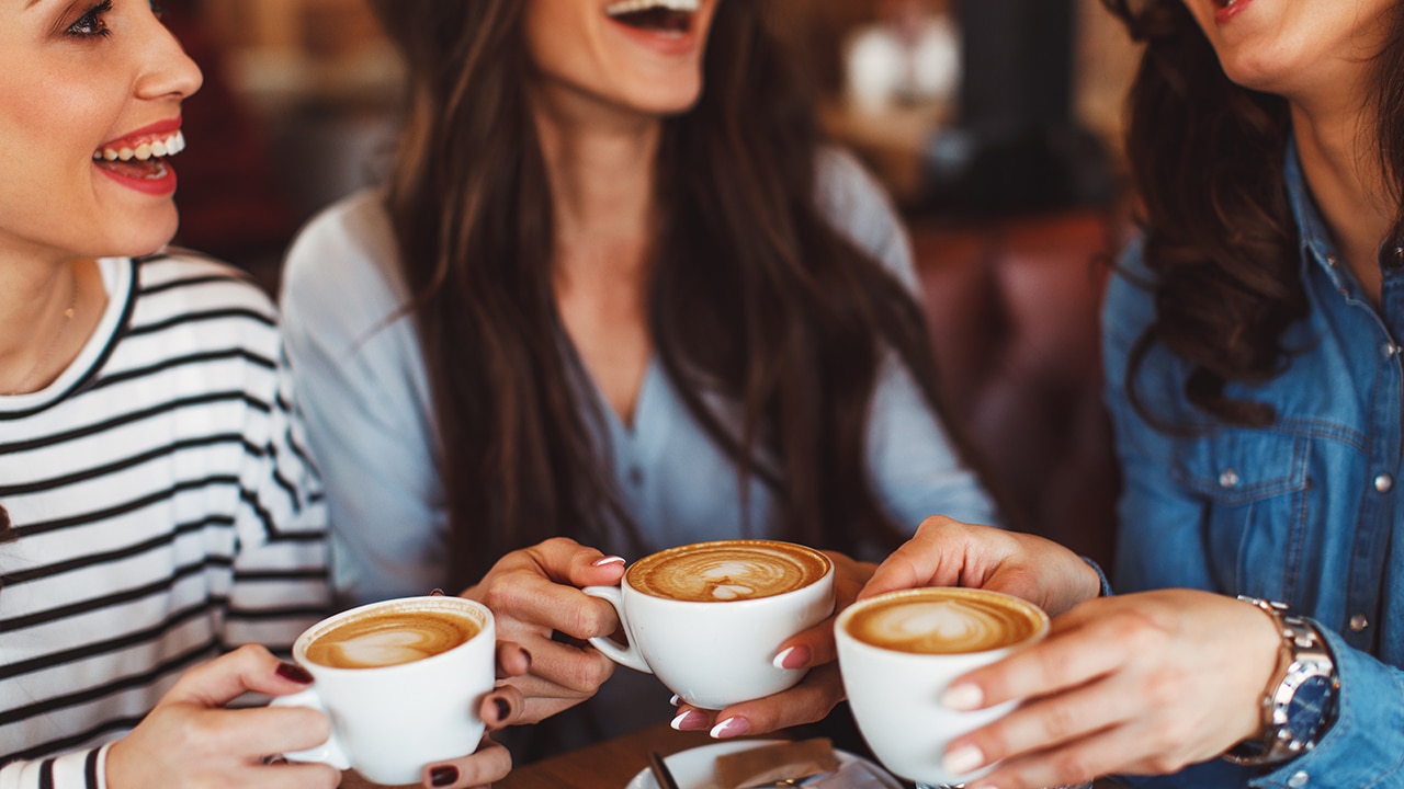 Three young women enjoy coffee at a coffee shop