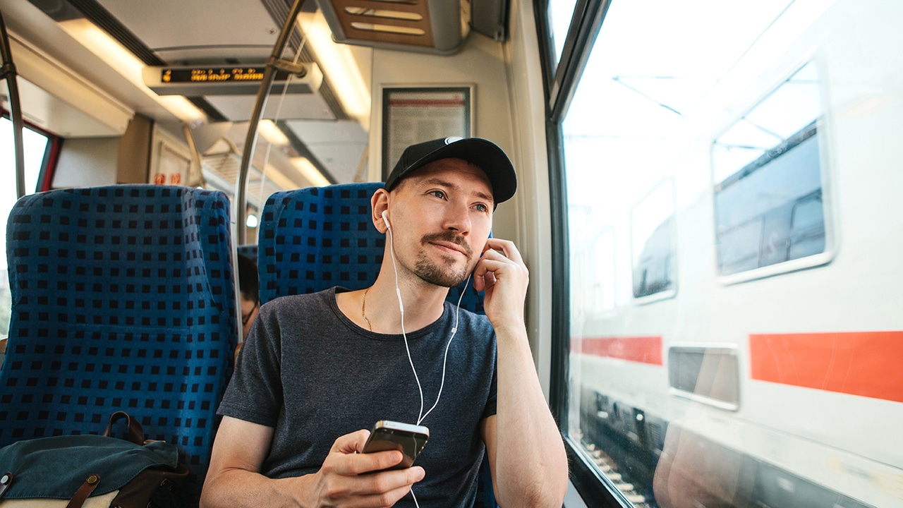 A young man listens to a music or podcast while traveling in a train.