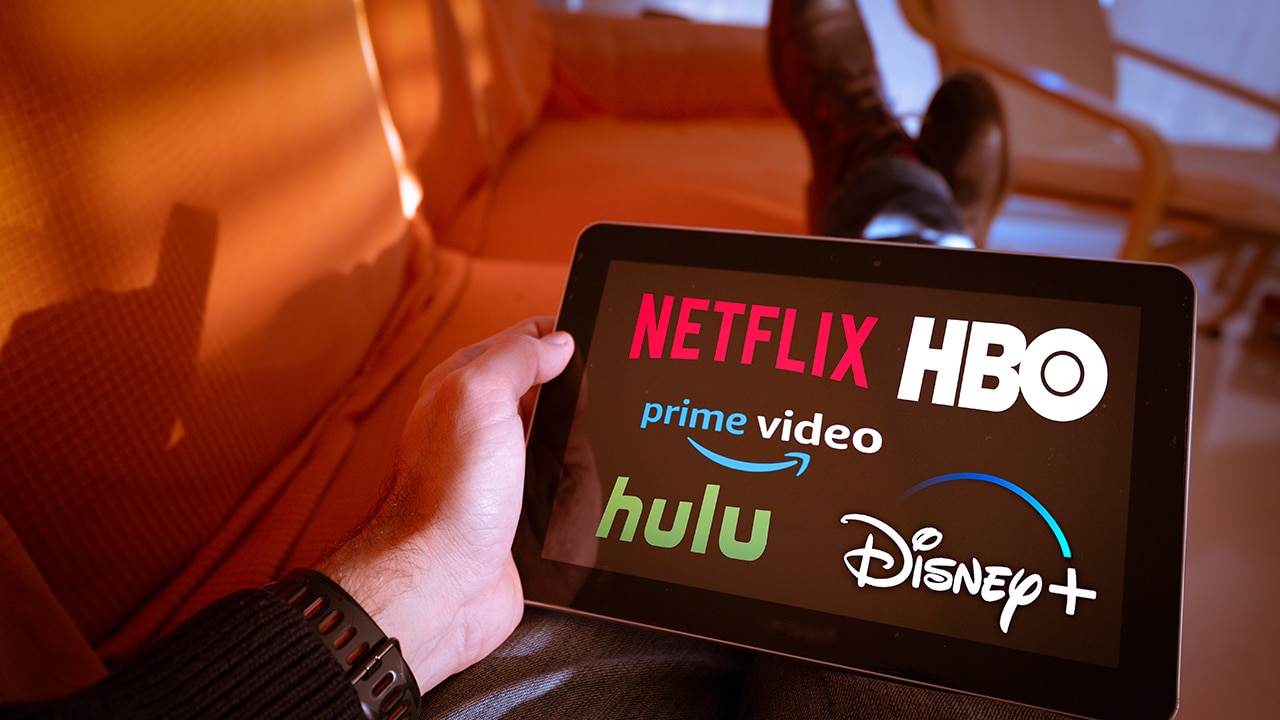 Man holds a tablet with Netflix hulu, amazon video, HBO and Disney+ logos on screen.Disney + is set to compete with other video streaming subscription services.