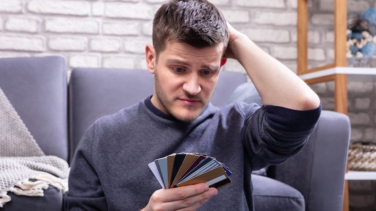 Stressed Man Looking At Too Many Credit Cards In Home