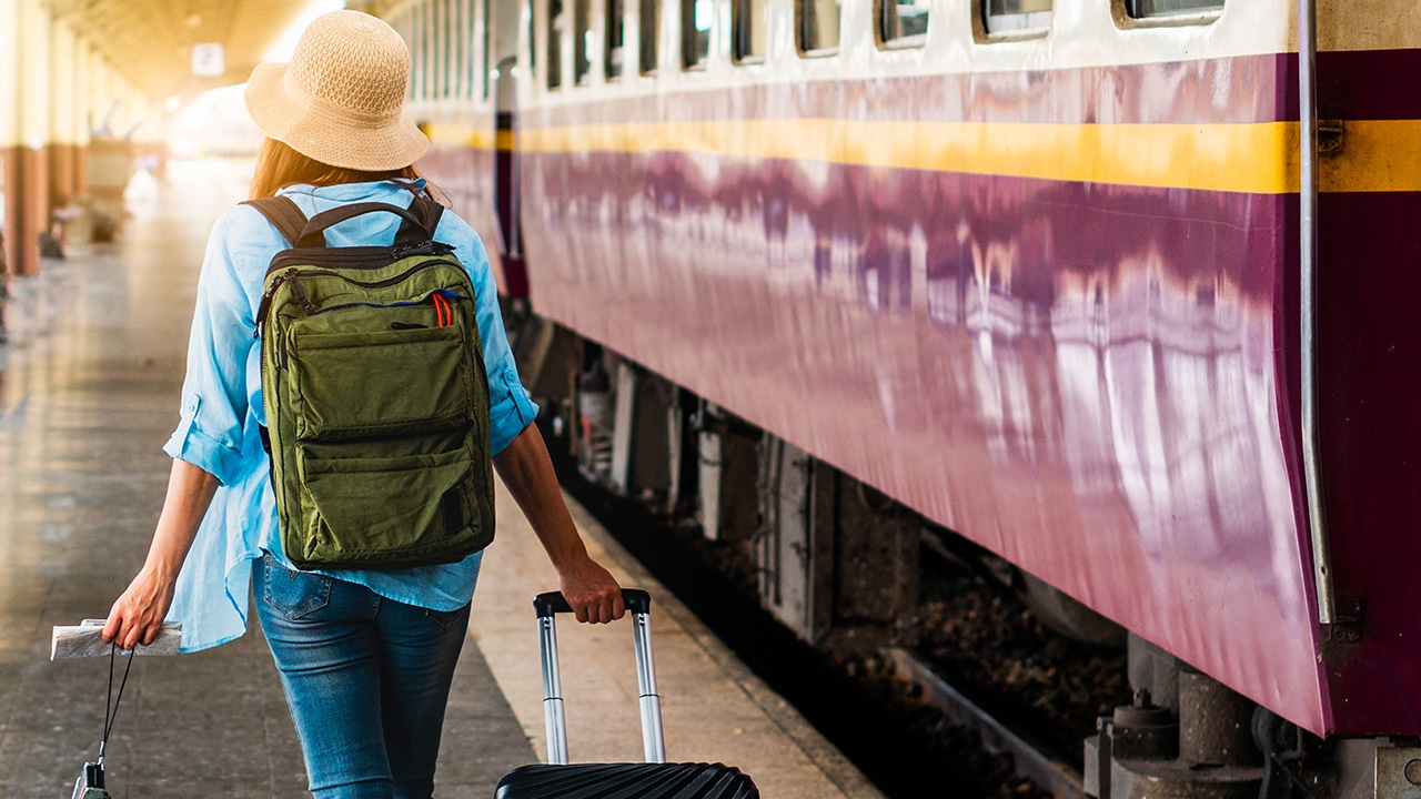 Solo woman backpacker traveler plan safety trip low cost budget summer holiday after coronavirus. Empty tourist on train railway platform. Use bus train sustainable environmental friendly transport
