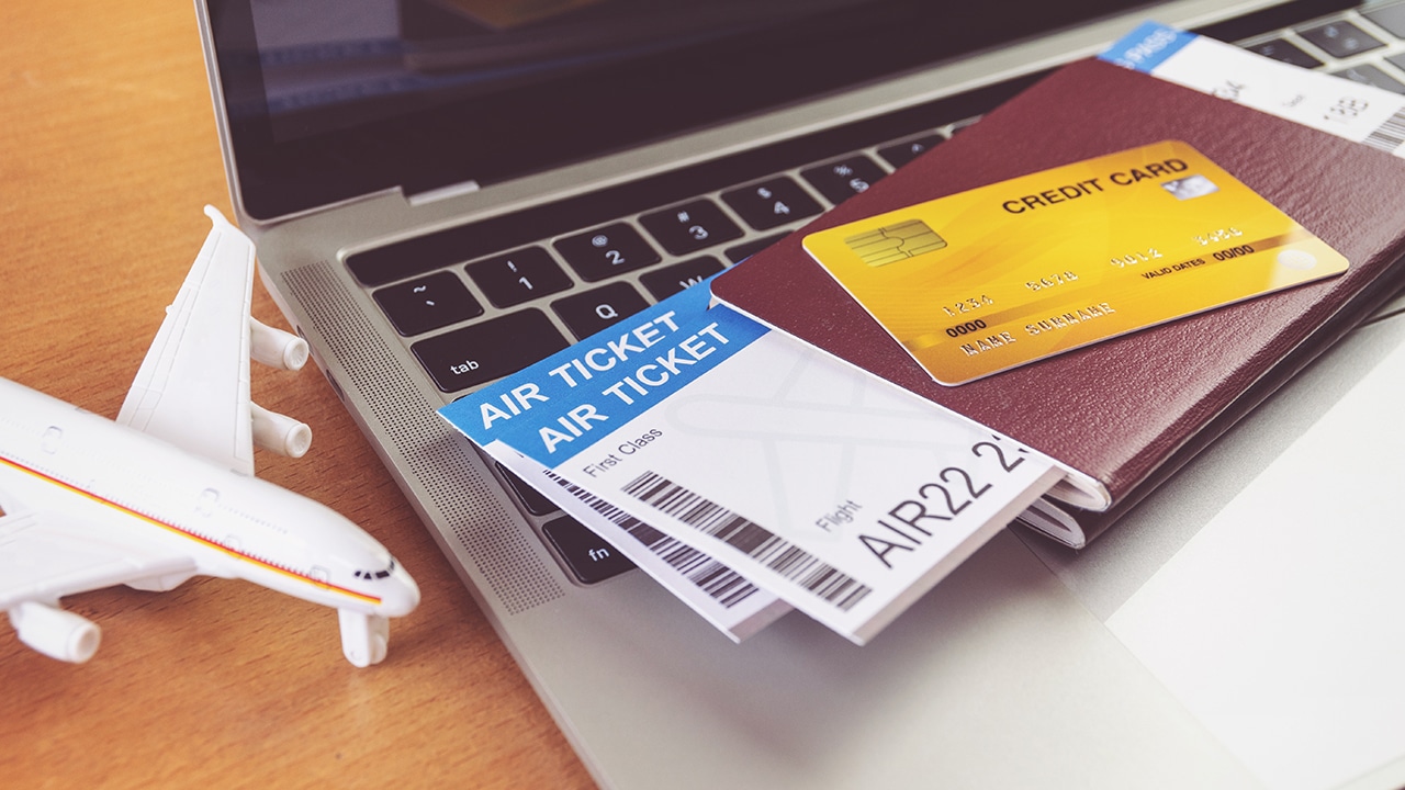 Air tickets and passports near laptop computer and airplane on table. Online ticket booking concept