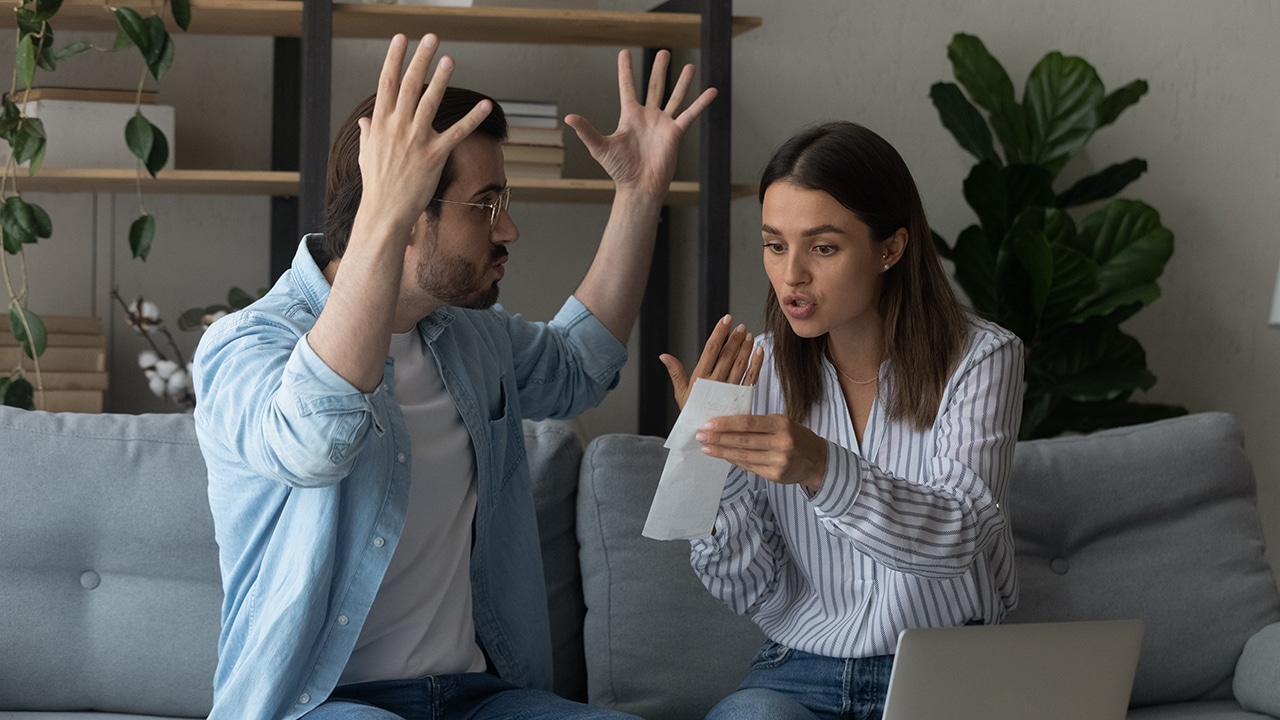 Stressed emotional couple arguing fighting when checking financial papers together finding unexpected debt lack of money on bank account. Mad angry husband scolding wife for overspending family budget