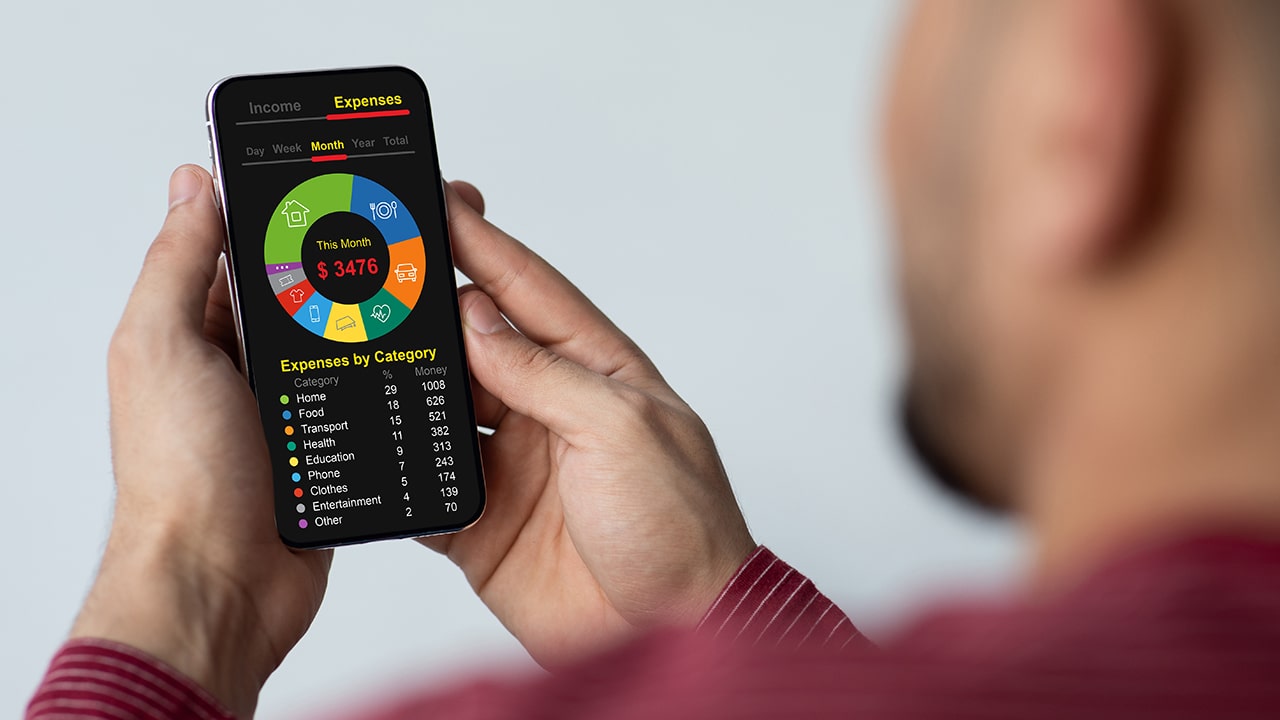 Unrecognizable man with cellphone calculating his family monthly spendings, checking expenses by categories, planning budget, using mobile application, over shoulder shot, creative image