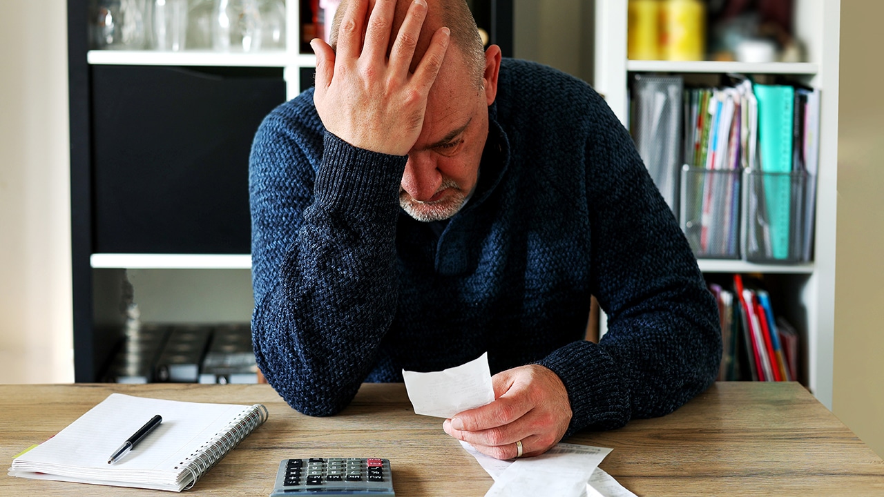 Man upset headache depressed from family cost got higher doing accounting holding receipts from supermarket with calculator by rising grocery prices and surging cost as an inflation financial crisis.