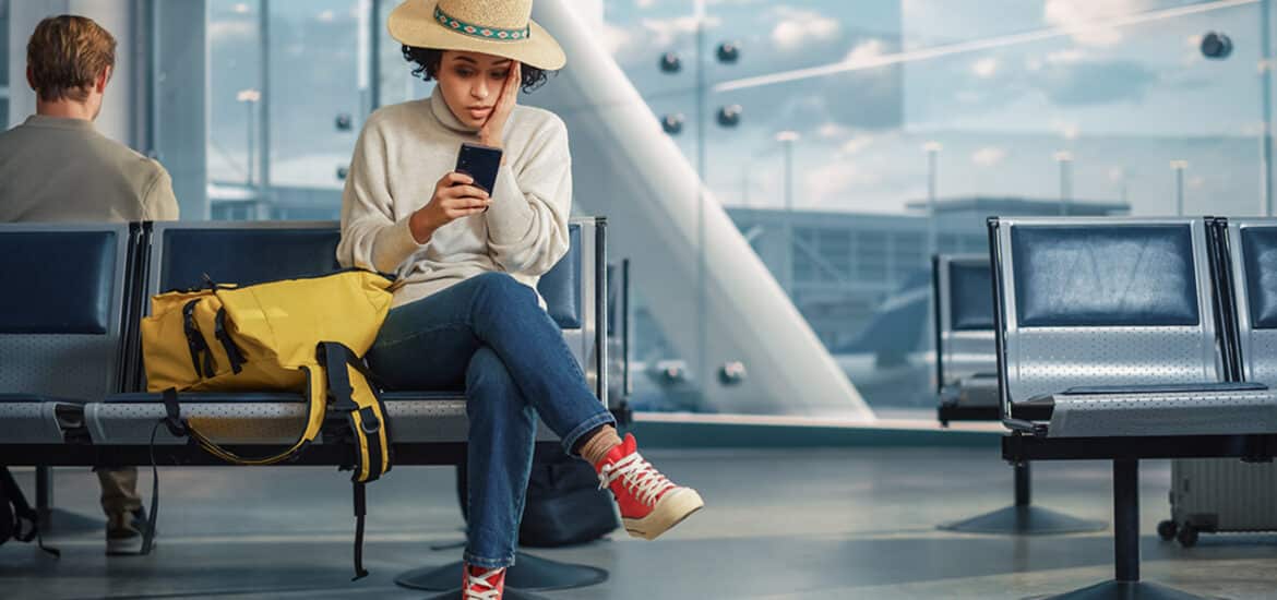 Airport Terminal: Woman Waits for Flight, Uses Smartphone, Receives Shockingly Bad News, Misses Flight. Upset, Sad, and Dissappointed Person Sitting in a Boarding Lounge of Airline Hub.