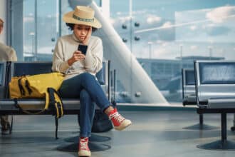 Airport Terminal: Woman Waits for Flight, Uses Smartphone, Receives Shockingly Bad News, Misses Flight. Upset, Sad, and Dissappointed Person Sitting in a Boarding Lounge of Airline Hub.