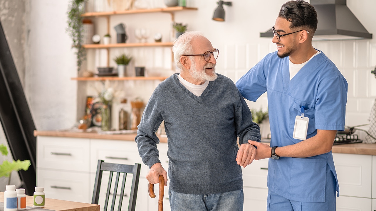 Medical worker helping his patient to move around the apartment