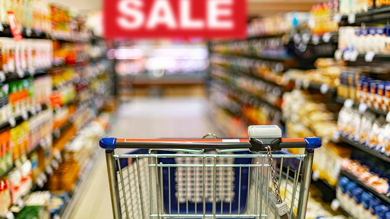 A shopping cart by a store shelf in a supermarket, sale sign at grocery