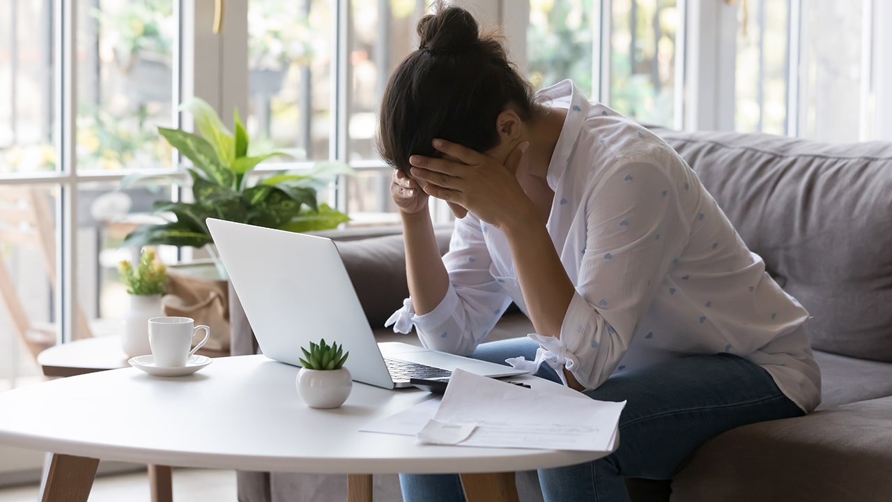 Stressed desperate broke business woman, homeowner getting frustrated at laptop at home, touching head, suffering from headache due to bad news. Financial problems, bankruptcy concept