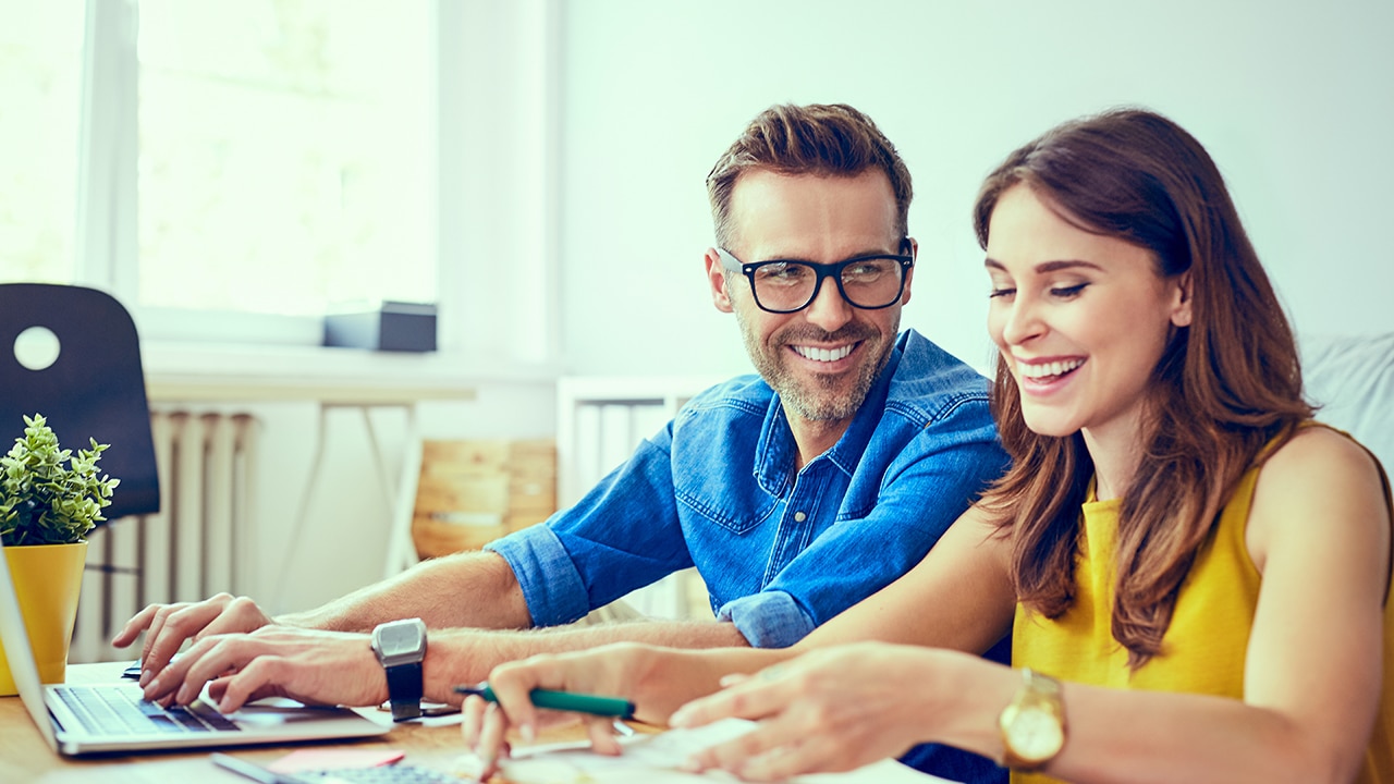 Couple setting financial goals together, working on computer, happy couple