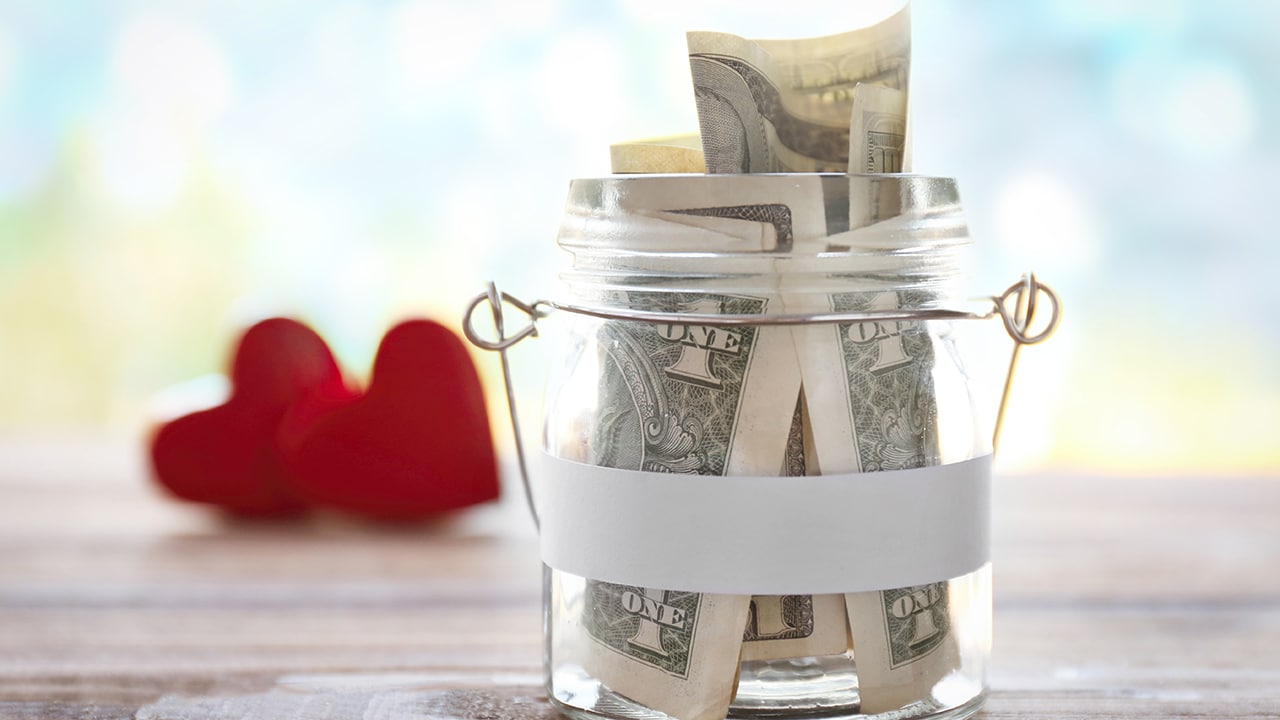 Glass jar with money on wooden table