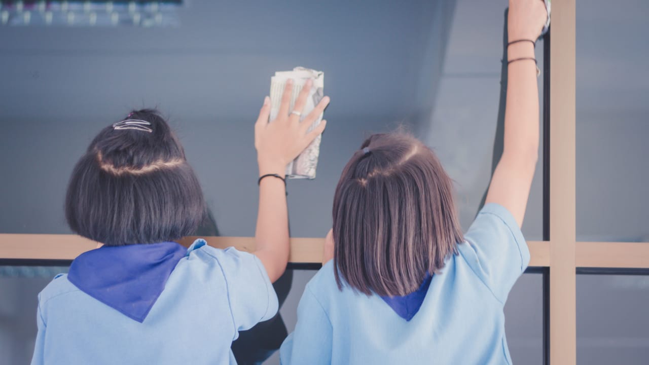 two women cleaning a window with newspapers