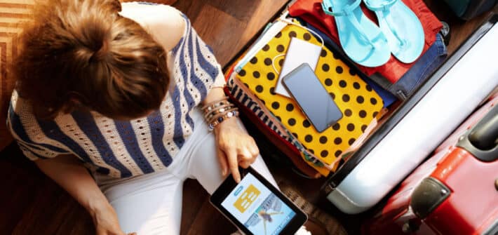 Woman with suitcase packed booking holiday