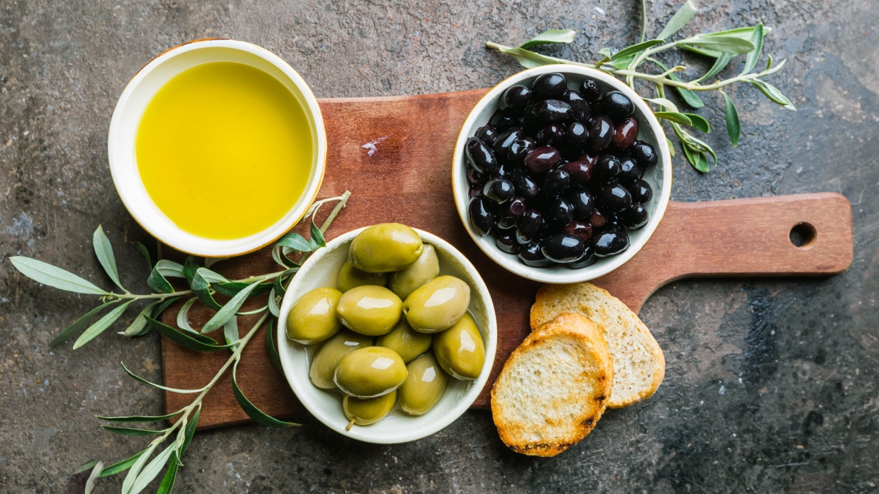 A set of Green and black olives and olive oil on a dark stone background
