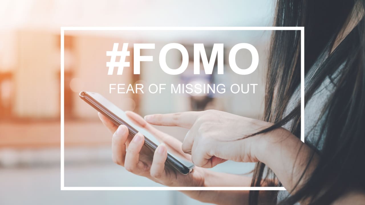 woman typing on mobile phone with the words #fomo fear of missing out in the forefront