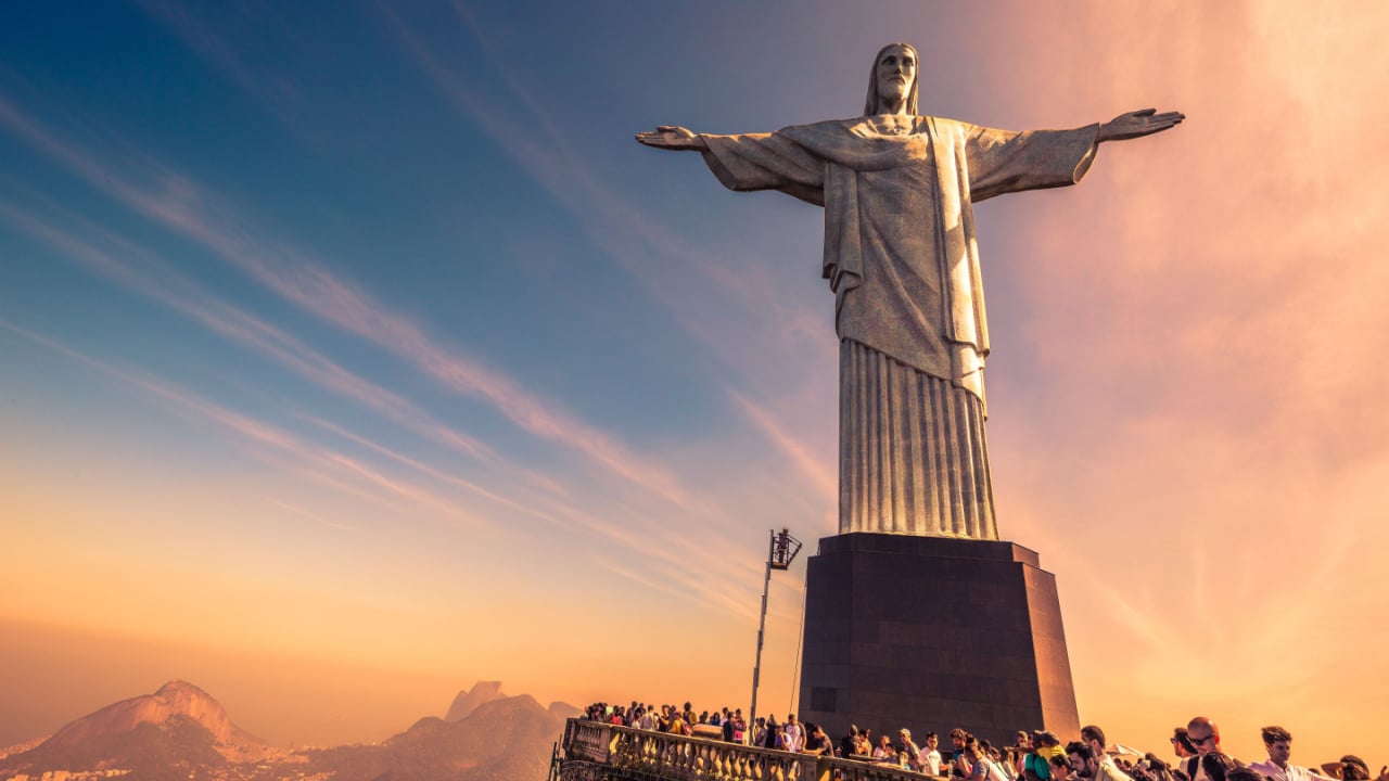 Sunset at Christ the Redeemer with beautiful warm sky and tourists gathering 