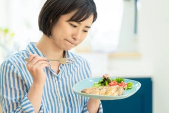 Woman looking unsure at a plate of healthy food.