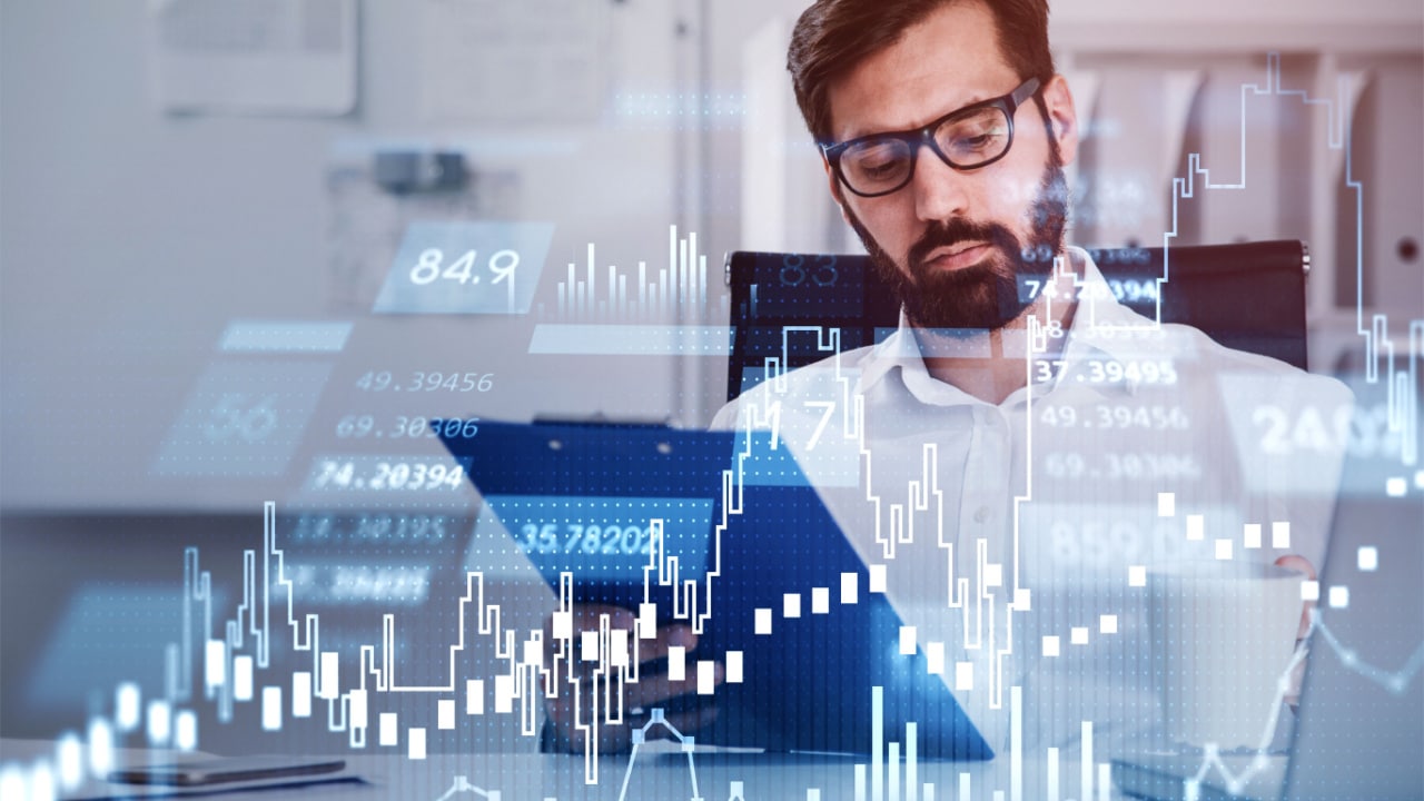 Man wearing glasses looking at investment charts