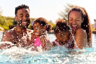 a man and woman with two children laughing and splashing in the water