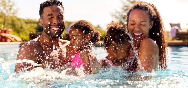 a man and woman with two children laughing and splashing in the water