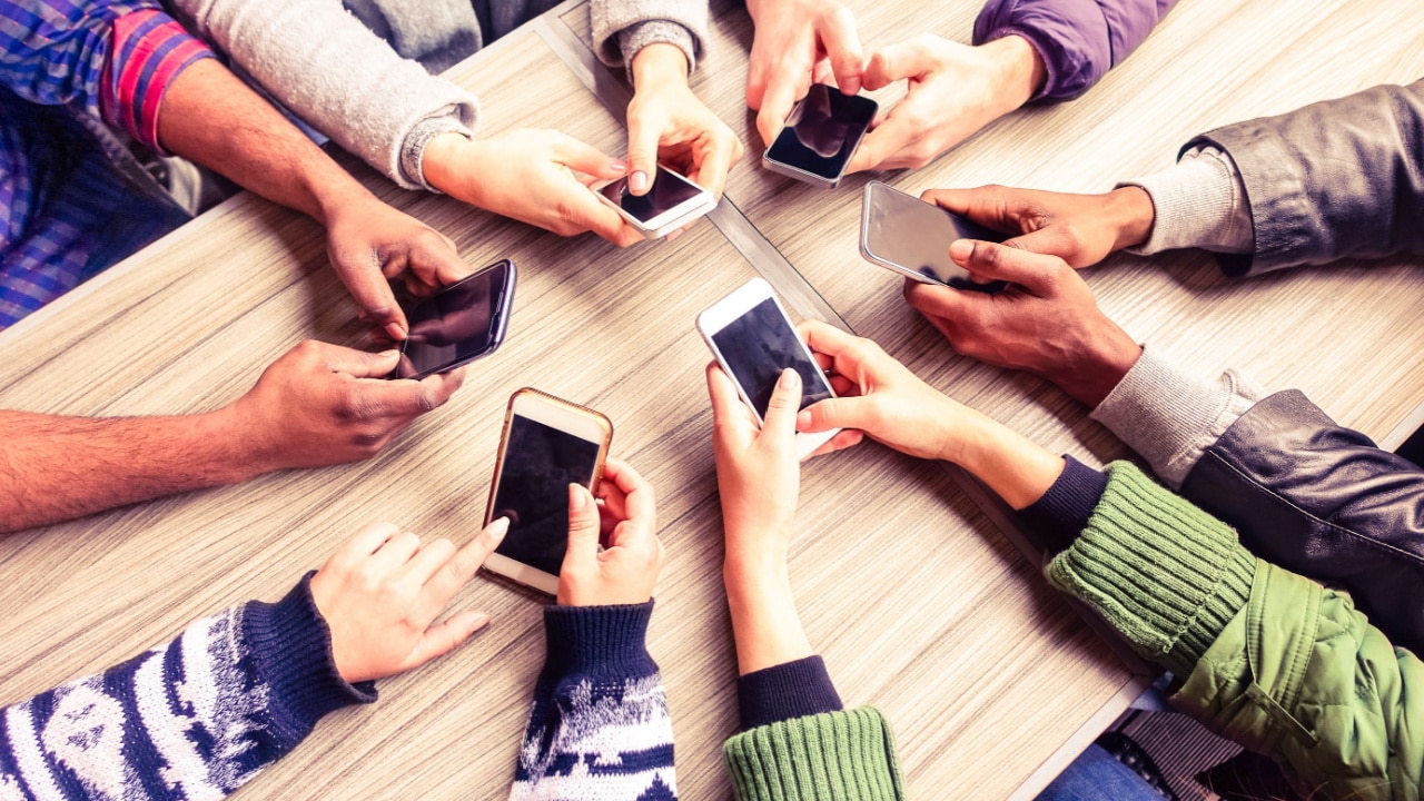 People sat round a table holding mobile phones