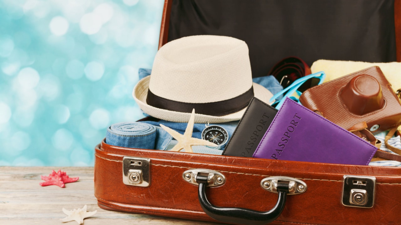 image showing an open suitcase with a hat, compass and various items