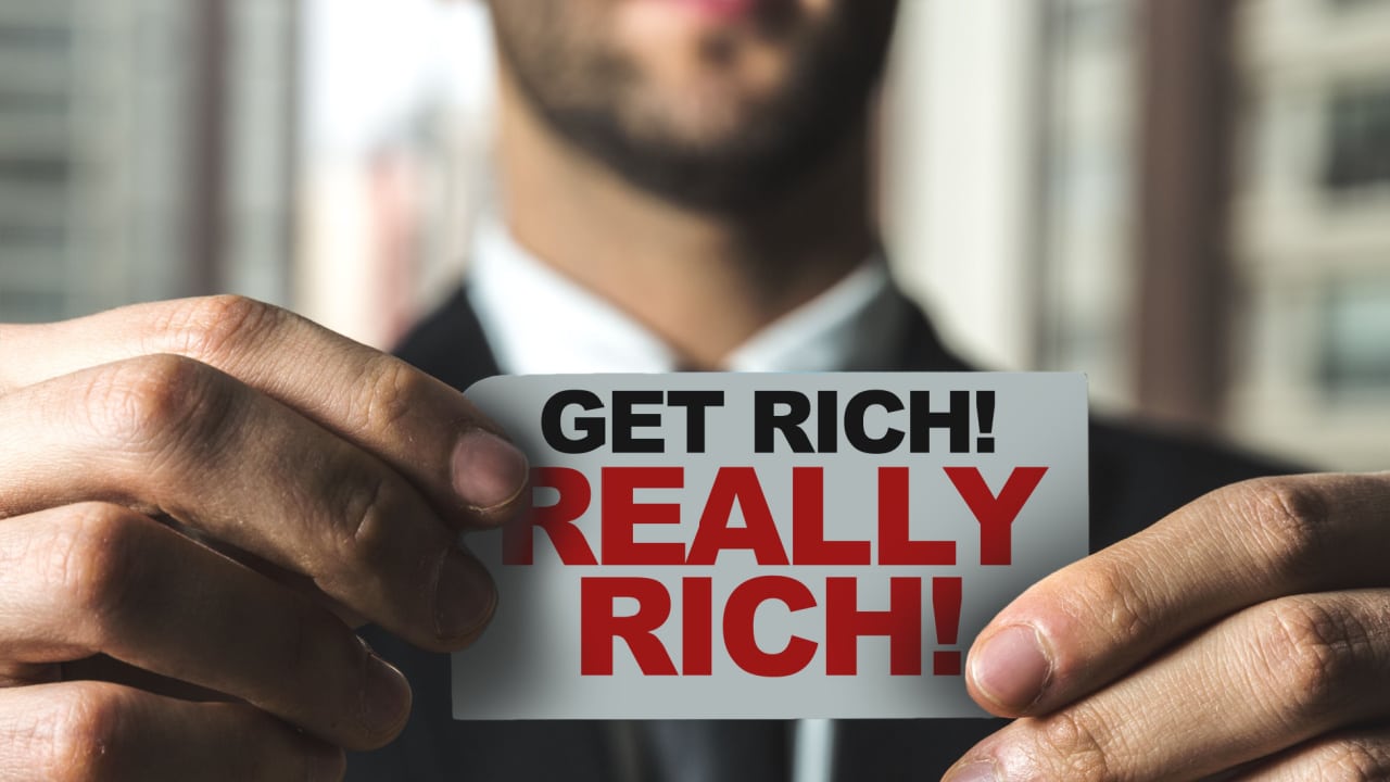 man holding a sign that says get rich really rich