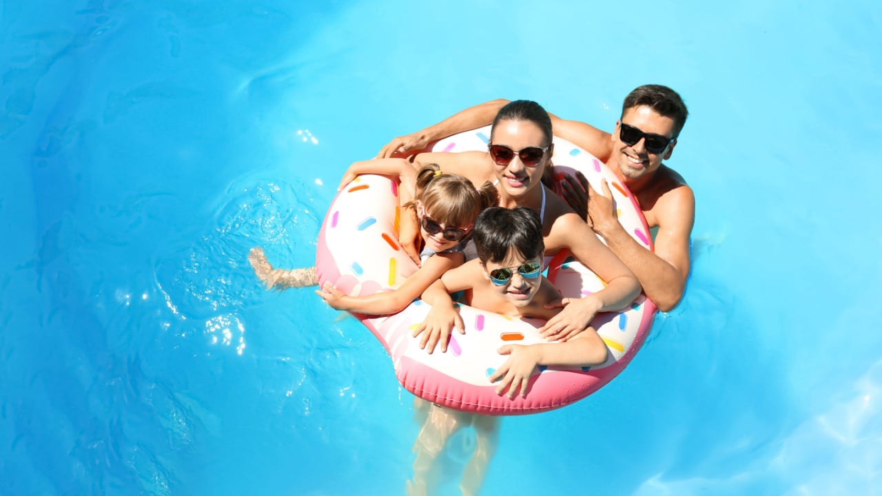 man, woman and two children playing in the water with an inflatable donut