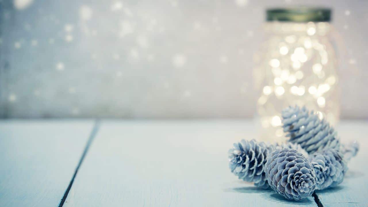 mason jar on a bathroom shelf with decorative pine cones