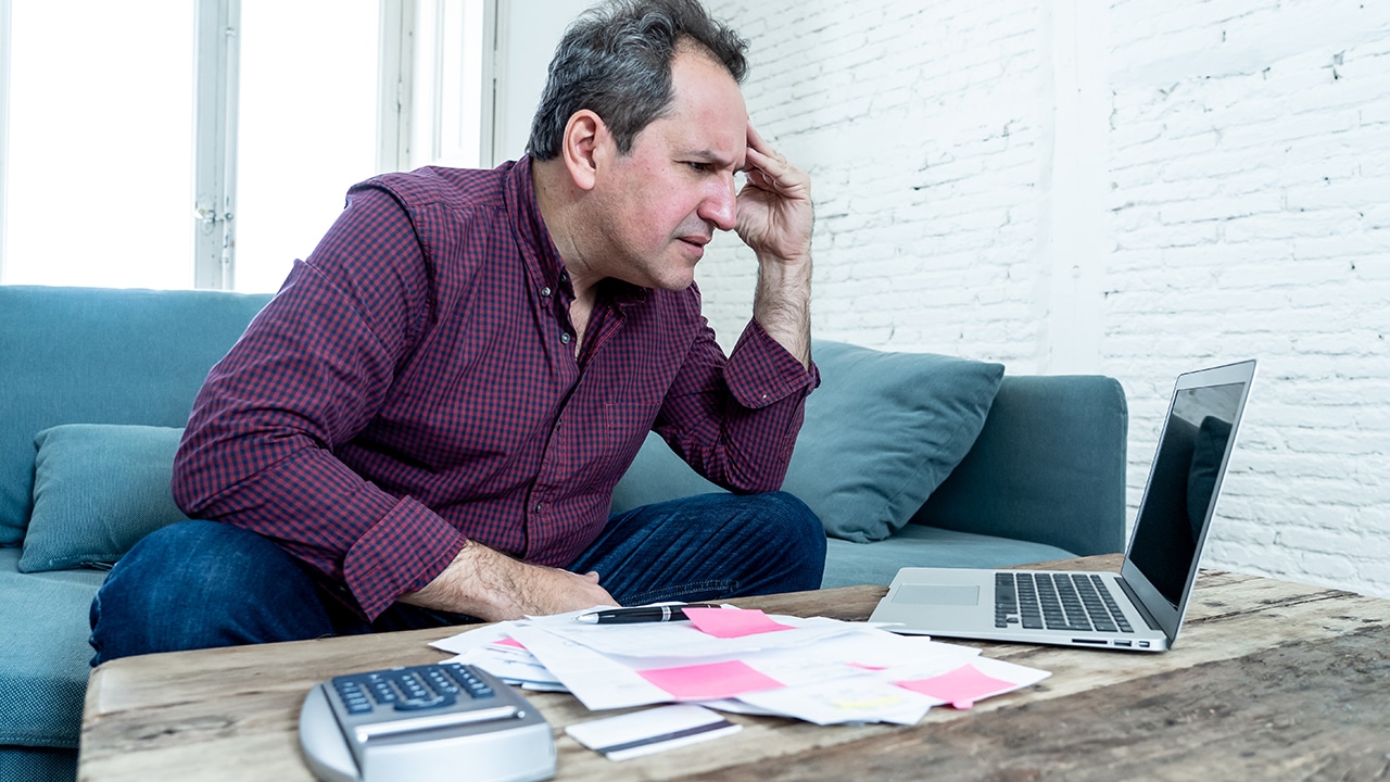 man on computer looking stressed and worried with credit card payments and home finances accounting costs charges taxes and mortgage in paying bills financial problems and debts.