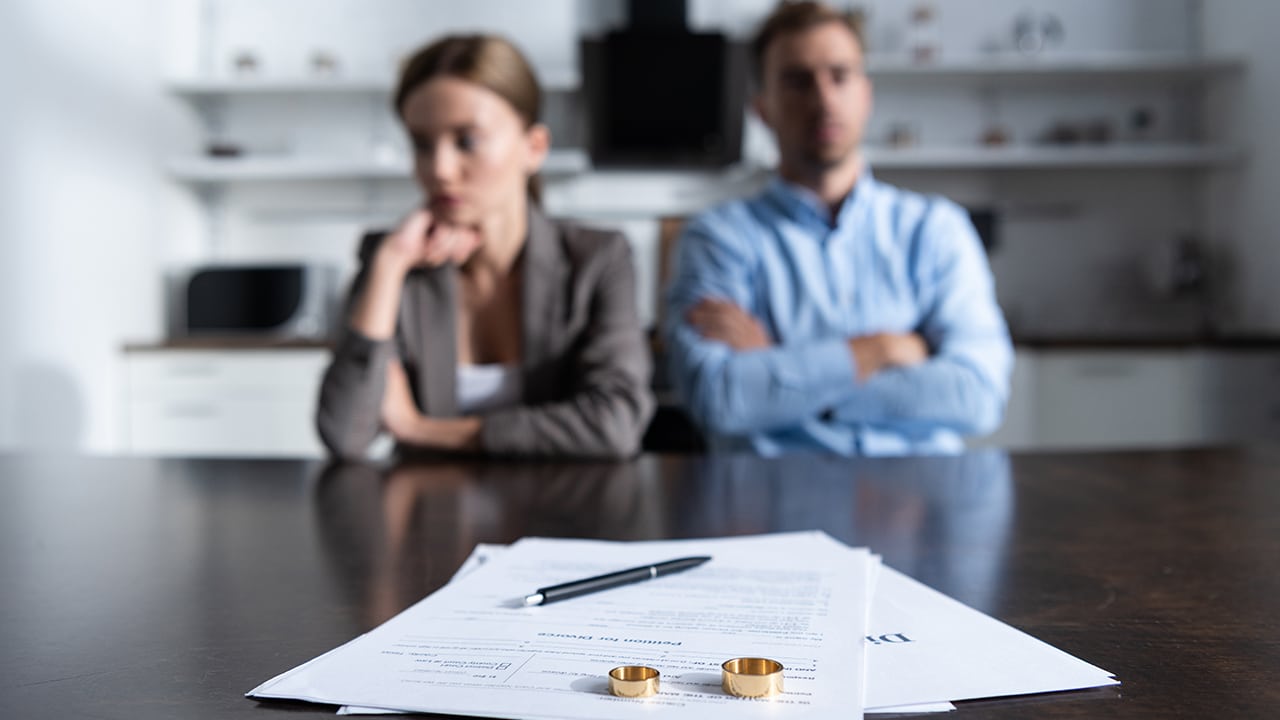 selective focus of couple sitting at table with divorce documents